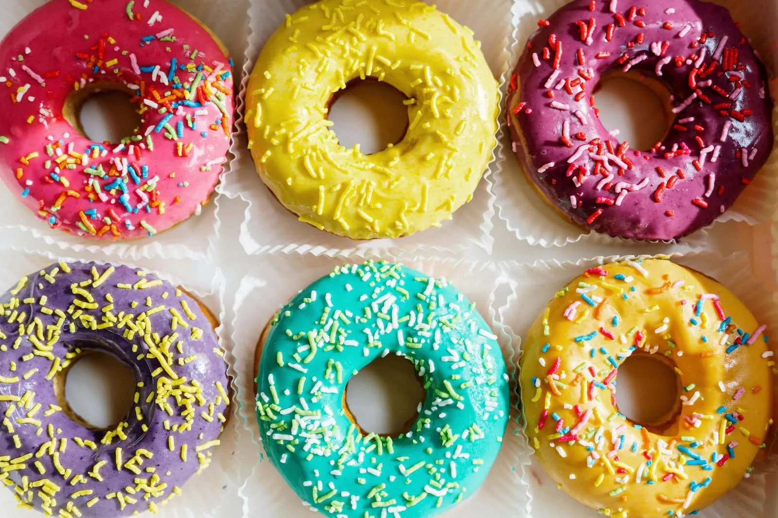A box with six donuts in different colors.