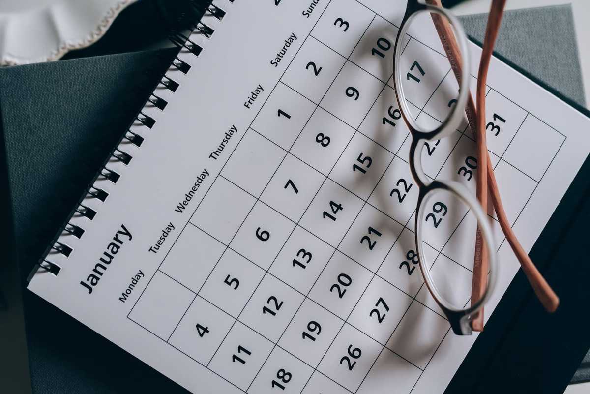 A desk calendar showing the month of January. There's a pair of glasses on the calendar.