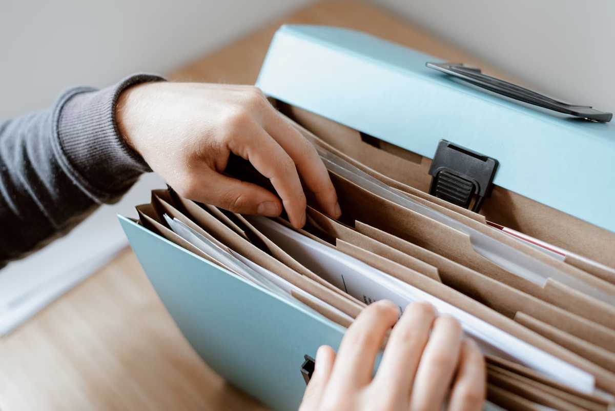 A person is looking for a document in a briefcase.