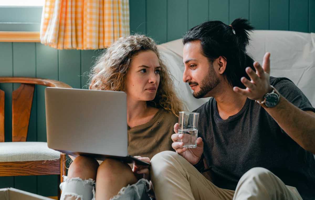 Two people discussing the HTML code on the laptop monitor in front of them.