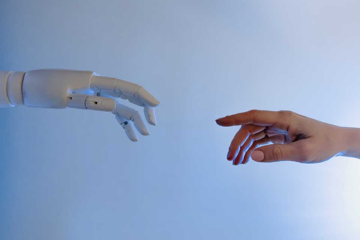 A human hand with an outstretched index finger approaches a robot hand.